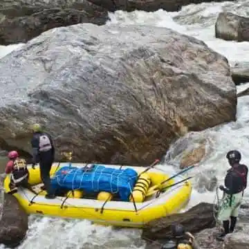 People maneuver a yellow raft through rocky rapids.